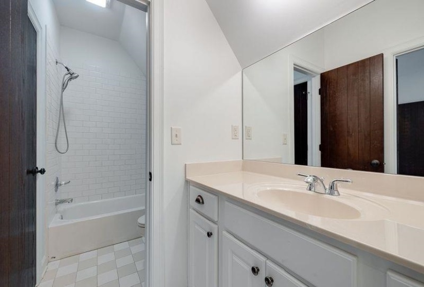 Full bathroom featuring vaulted ceiling, tiled shower / bath combo, vanity, and toilet