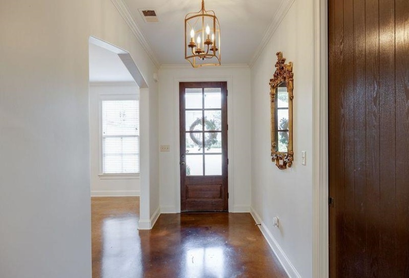 Doorway to outside featuring ornamental molding and a notable chandelier