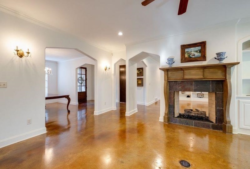 Unfurnished living room featuring ceiling fan, ornamental molding, concrete flooring, and a tiled fireplace