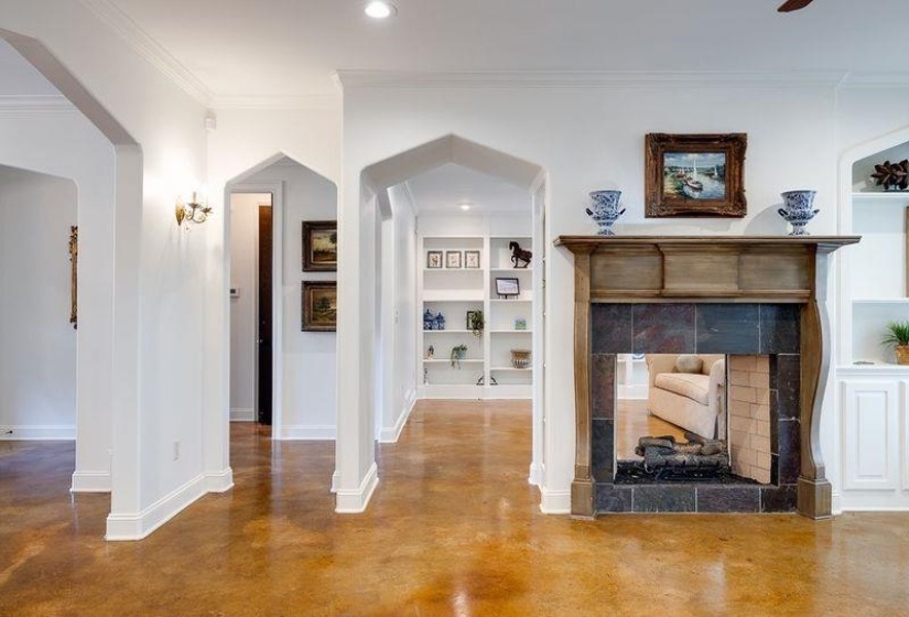Unfurnished living room with built in shelves, ornamental molding, concrete floors, and a tile fireplace