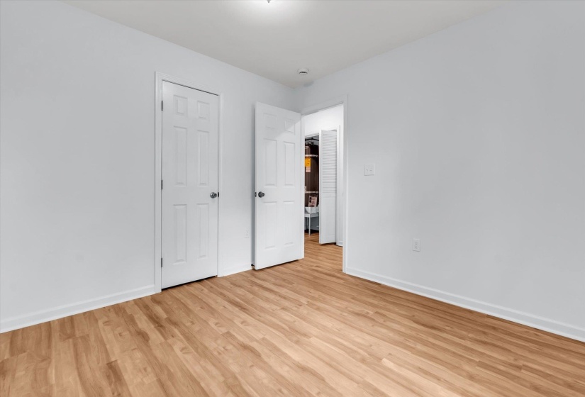 Bright room with wood-finish flooring, white baseboards, and white paneled doors