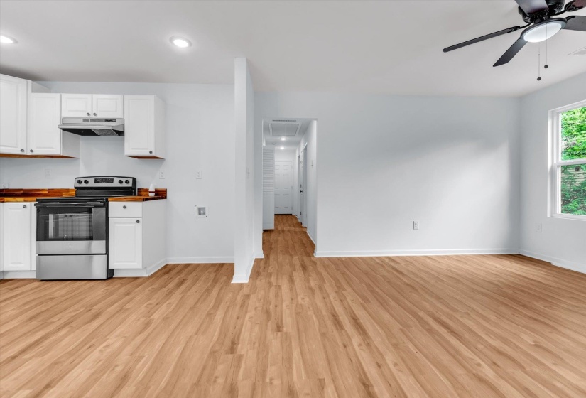 Open-concept living space with wood-finish flooring, a contemporary ceiling fan, and ample natural light from a large window