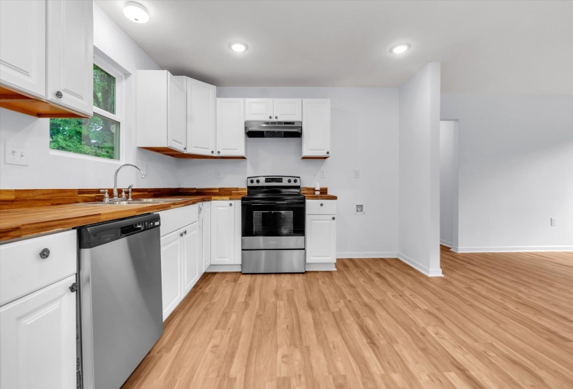 Kitchen featuring white cabinetry, wood-finish countertops, stainless steel appliances, and wood-finish flooring