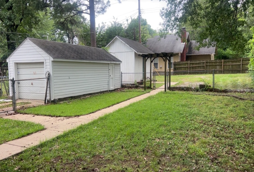 Detached garage with white siding and an asphalt shingle roof