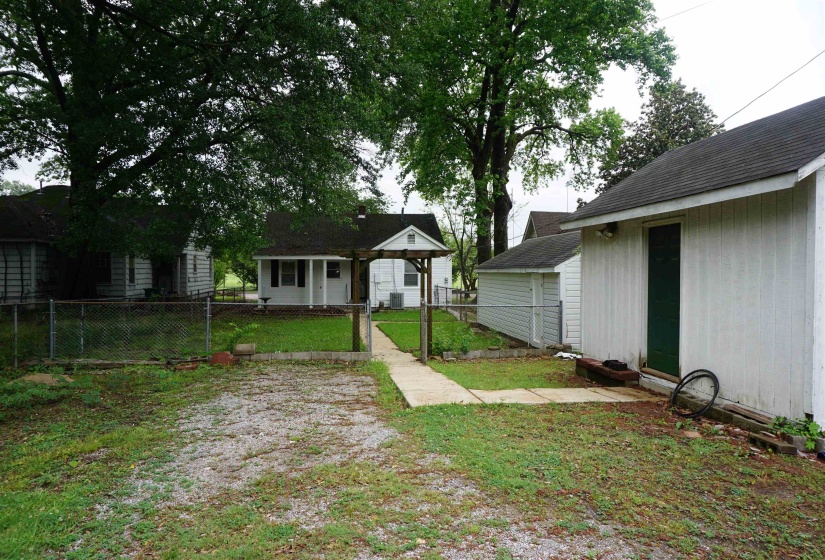 Gravel driveway with a concrete walkway leading to a fenced yard