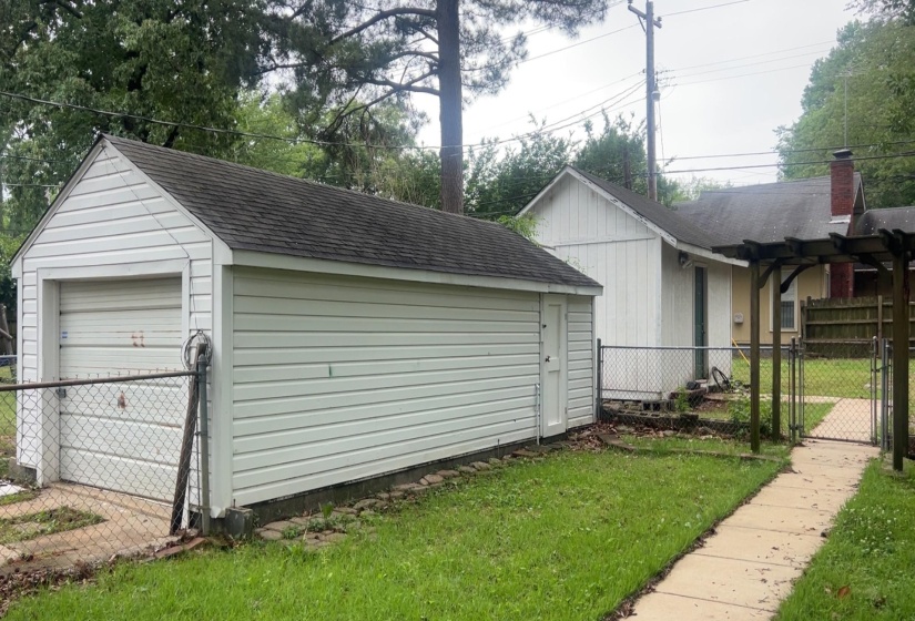 Detached garage with horizontal siding, a roll-up door, and a shingled roof