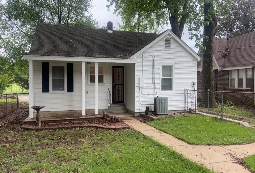 White siding exterior with a dark shingle roof, featuring a covered front porch with white columns and dark shutters