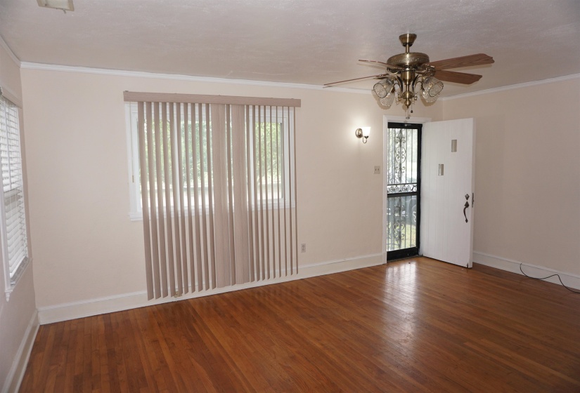 Hardwood flooring throughout, featuring a ceiling fan with integrated lighting, wall sconce, and white trim
