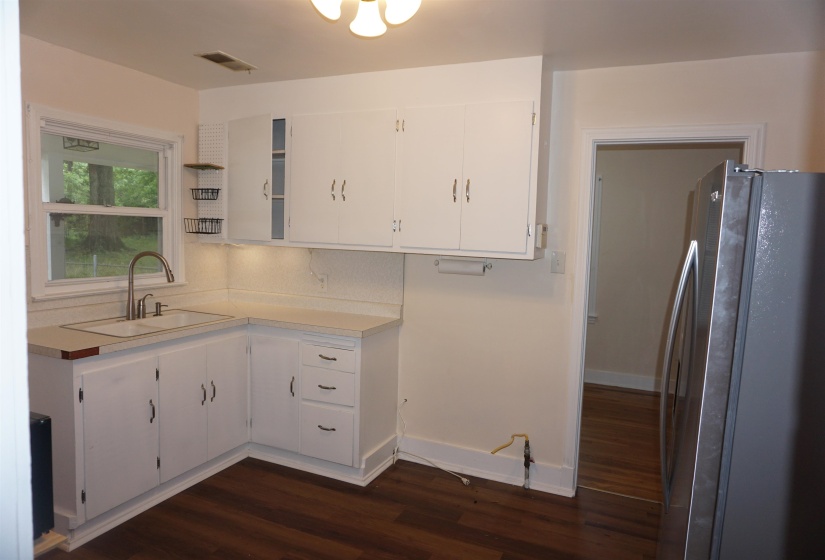 Kitchen featuring white cabinetry with dark hardware, a stainless steel faucet, and a light-toned countertop