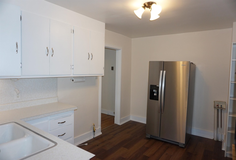 Kitchen area featuring white cabinetry, a double basin sink, light-toned countertops, wood-finish flooring, and a flush mount ceiling light fixture