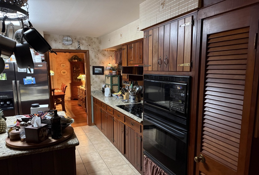 Kitchen featuring wood cabinetry, light granite-finish countertops, and tile flooring