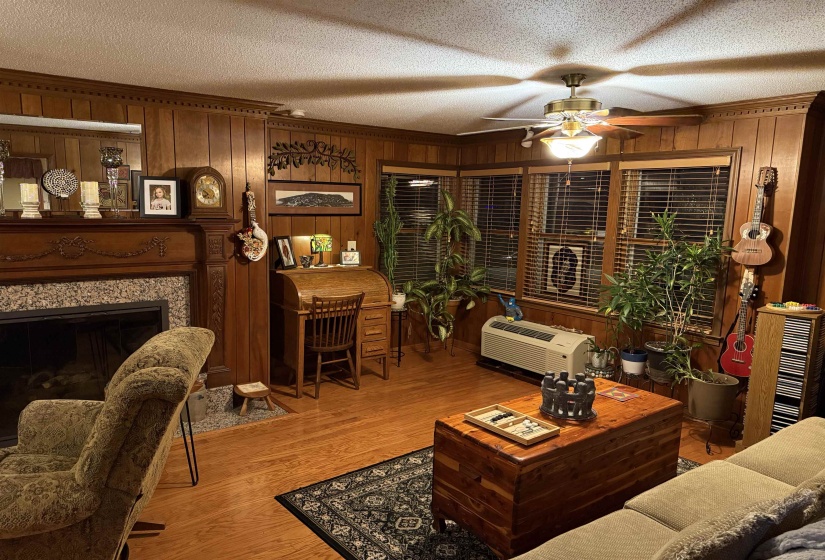 Living area featuring wood paneling, wood-finish flooring, and multiple windows with blinds