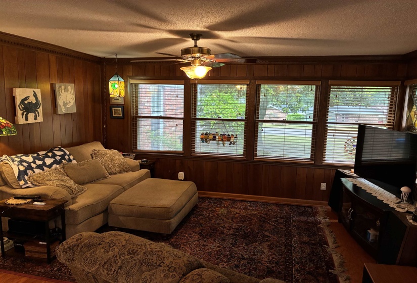 Wood paneling and crown molding accent this space with multiple windows