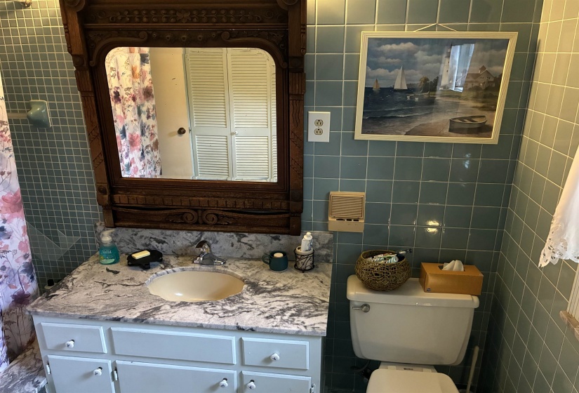 Bathroom with a stone-finish vanity top, white cabinetry, and a carved wood-finish mirror