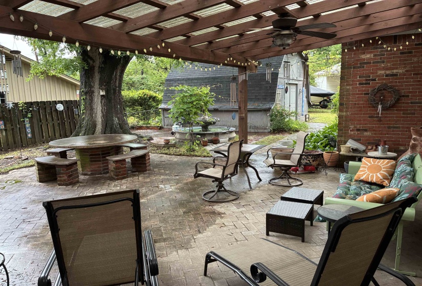Expansive brick patio with a wood pergola featuring a ceiling fan