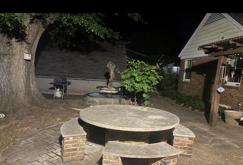 Brick paver patio featuring a circular stone table with integrated seating