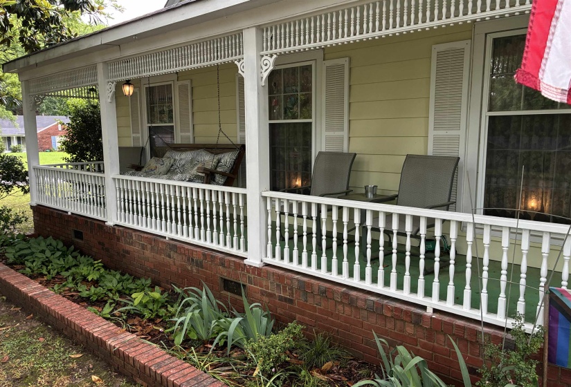 Inviting front porch featuring a white spindle railing and a porch swing
