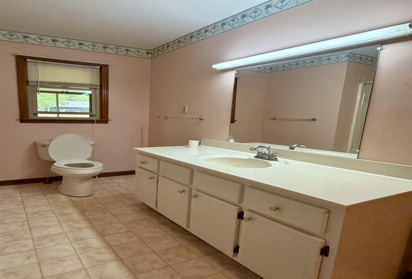 Bathroom featuring a vanity with an integrated sink, a large mirror, and tiled flooring
