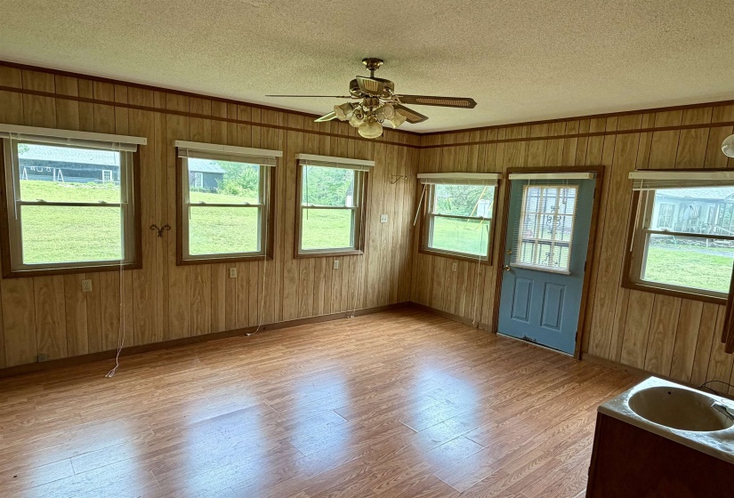 Room featuring wood-finish flooring, paneled walls, and multiple windows