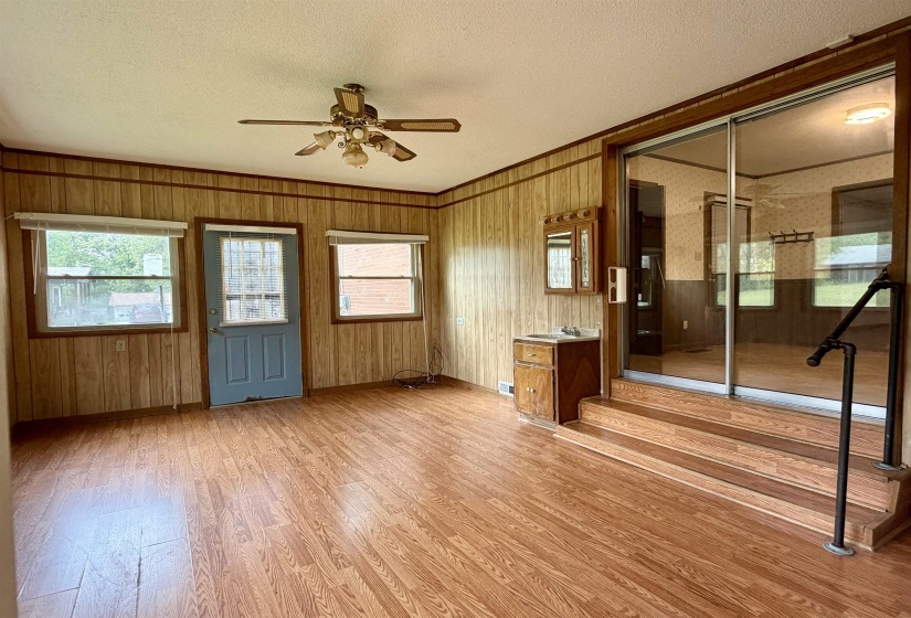 Room with wood-finish flooring and paneling, featuring a ceiling fan