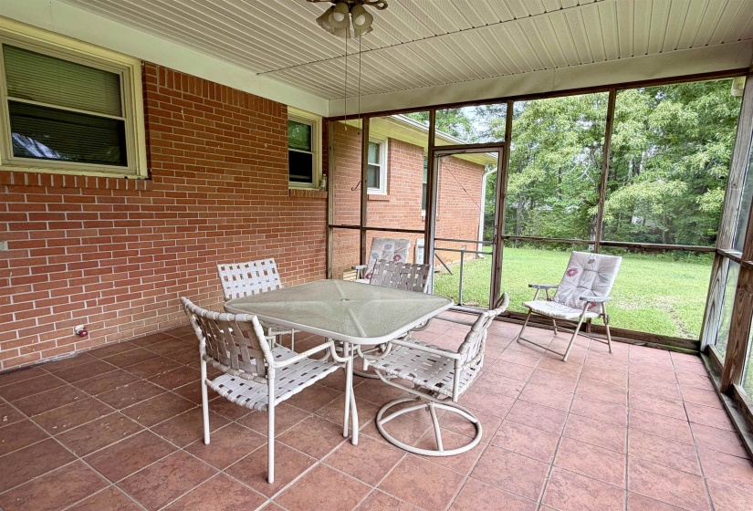Screened porch with brick exterior wall, tile flooring, and a ceiling fan