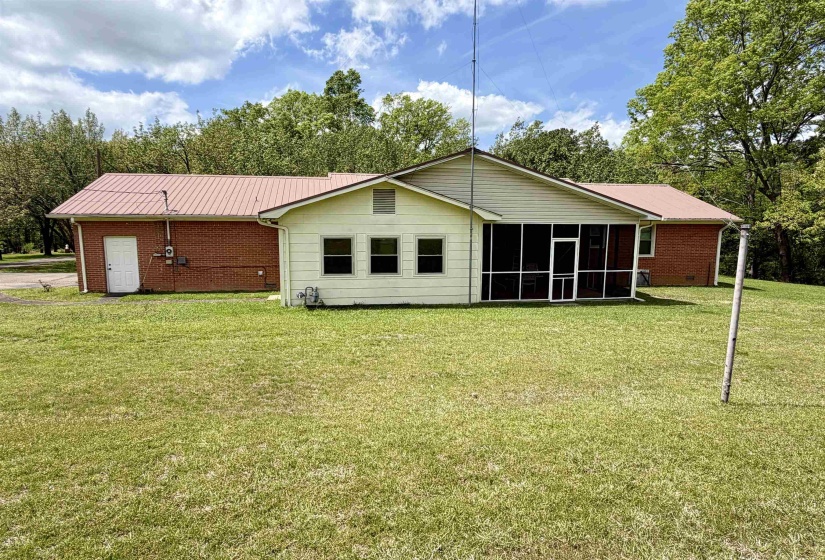 Rear exterior featuring a screened porch, brick and siding finishes, and a metal roof