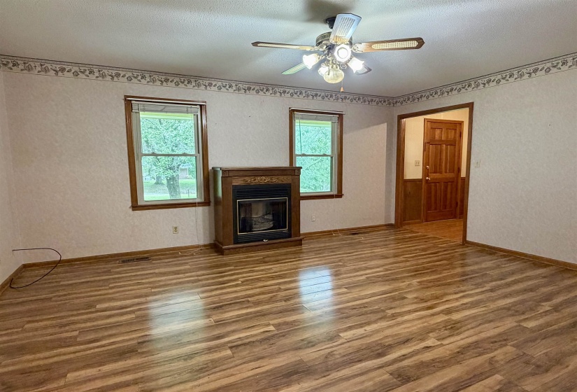 Spacious room featuring wood-finish flooring, an ornate fireplace, and two windows with wood trim