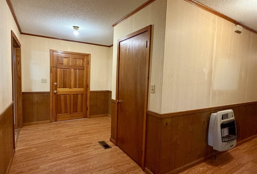 Entryway featuring a paneled wood door, wood-finish flooring, and wood wainscoting