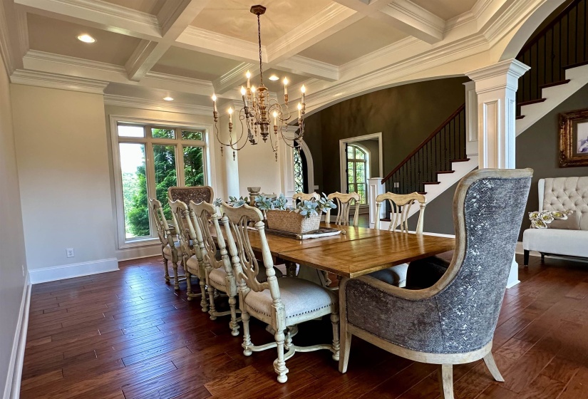 Dining space with healthy amount of natural light, beamed ceiling, stairway, dark wood-style floors, and arched walkways