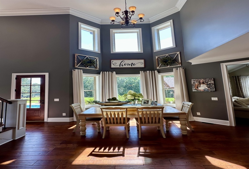 Dining area featuring crown molding, dark wood finished floors, plenty of natural light, a towering ceiling, and a chandelier