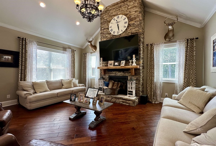 Living area featuring ornamental molding, a fireplace, high vaulted ceiling, dark wood finished floors, and a chandelier