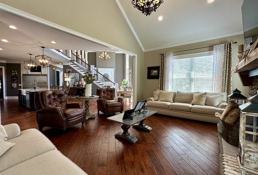 Living room featuring a chandelier, stairs, ornamental molding, recessed lighting, and dark wood-style flooring