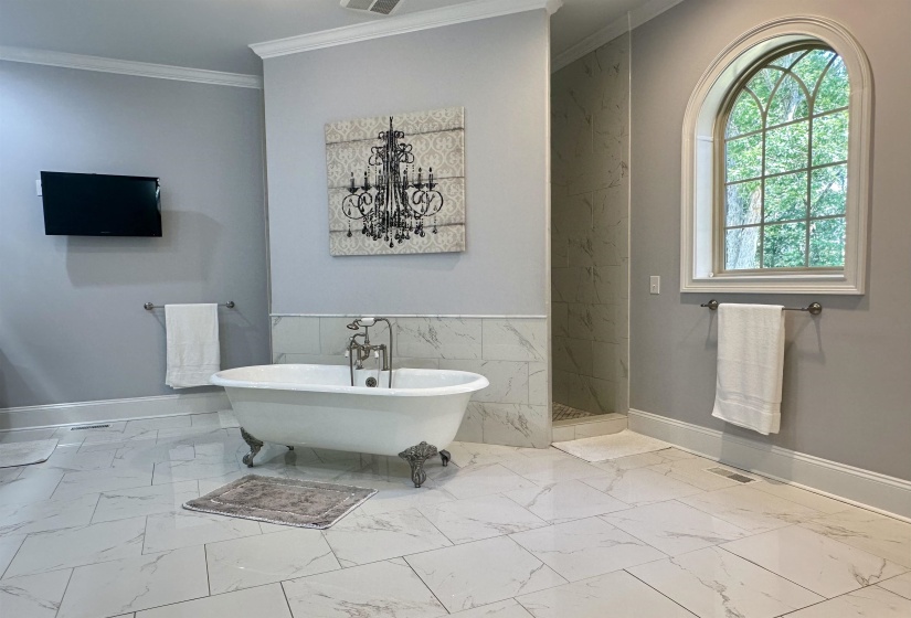 Full bath with a freestanding bath, light marble finish floors, ornamental molding, tile walls, and a marble finish shower