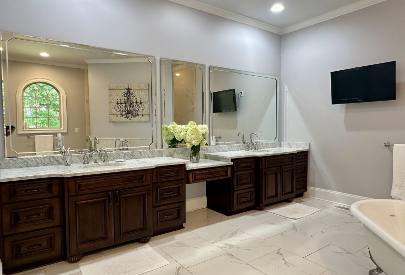 Full bath with crown molding, a soaking tub, double vanity, light marble finish floors, and recessed lighting