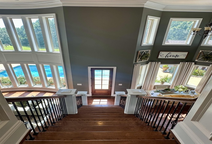 Stairway with crown molding, wood finished floors, a high ceiling, and a chandelier