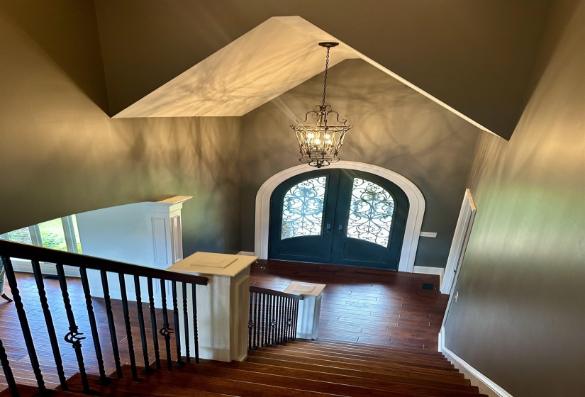 Entryway featuring french doors, dark wood finished floors, a chandelier, arched walkways, and a high ceiling