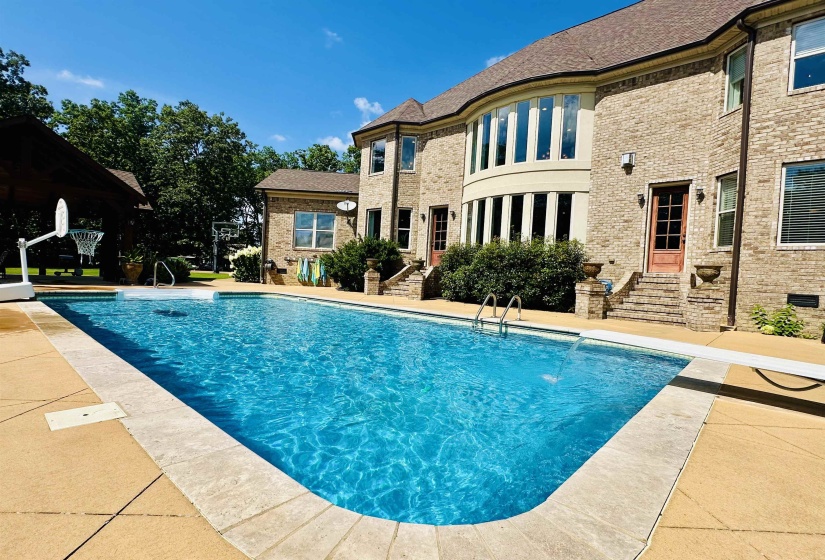 Rear view of house with brick siding, an outdoor pool, a patio, and entry steps