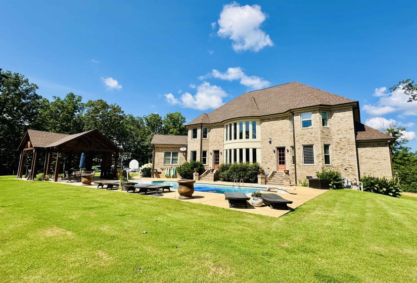 Back of house featuring a patio area, an outdoor pool, a lawn, and brick siding
