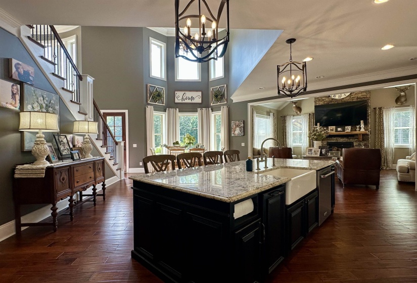 Kitchen with dark cabinets, light stone counters, ornamental molding, open floor plan, and a fireplace