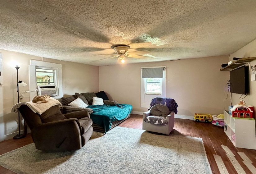 Living area with wood-finish flooring, light-colored walls, and a ceiling fan with integrated lighting
