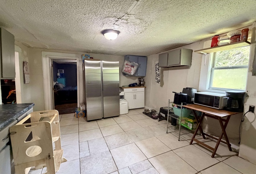 Kitchen featuring tile flooring, a window providing natural light, and cabinetry with dark countertops