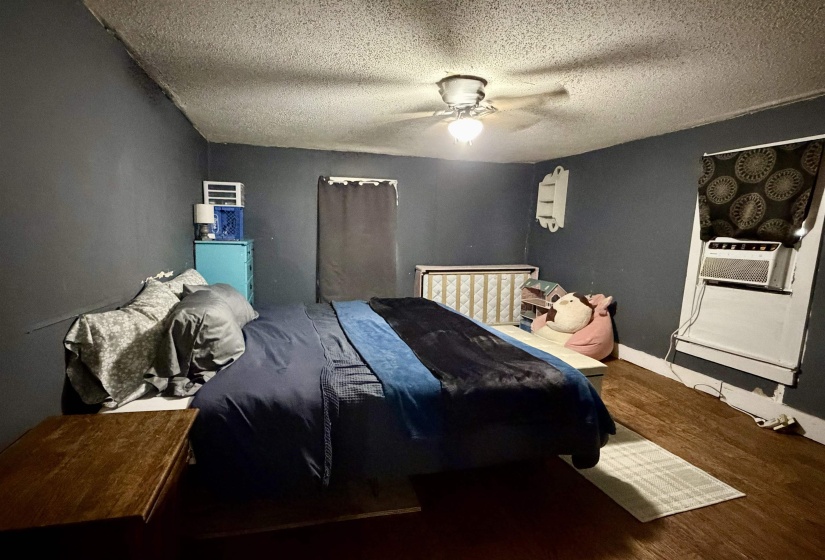 Room featuring dark-toned walls, wood-finish flooring, and a ceiling fan with integrated lighting