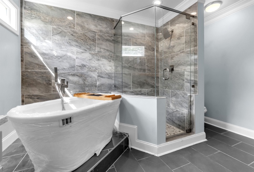 Freestanding soaking tub and glass-enclosed shower with full-height tile surround