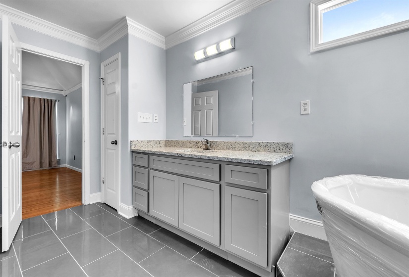 Bathroom vanity with a light gray cabinet, speckled countertop, and rectangular undermount sink