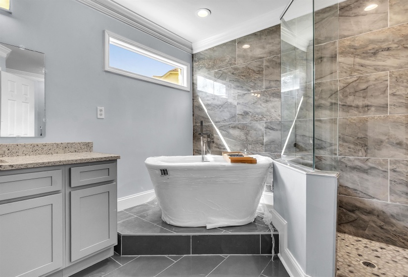 Freestanding soaking tub with a tiled surround and full glass shower enclosure