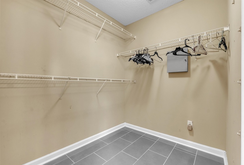 Walk-in closet featuring wire shelving, hanging rods, and grey tile flooring