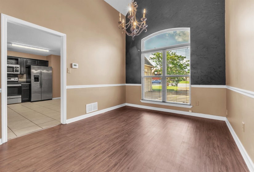 Dining area featuring wood-finish flooring, two-tone walls with chair rail molding, and an arched window with blinds