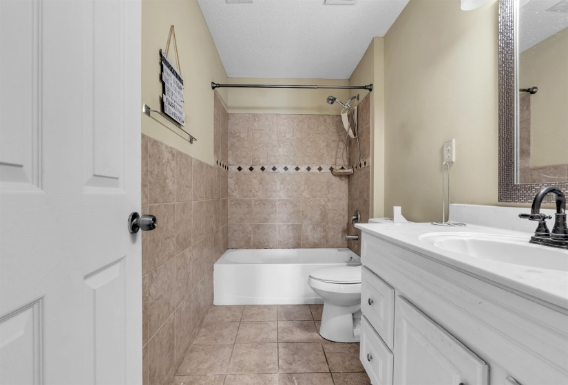 Bathroom featuring a white vanity with integrated sink, dark-toned faucet, and framed wall mirror
