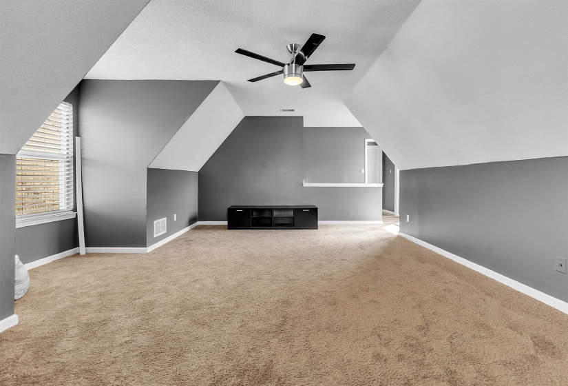 Carpeted room featuring a ceiling fan with light, sloped ceilings, a window with blinds, and painted walls