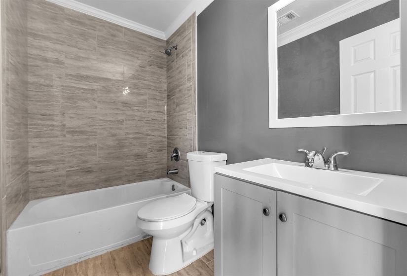 Bathroom featuring a single vanity with light gray cabinetry, an integrated sink, and a framed mirror